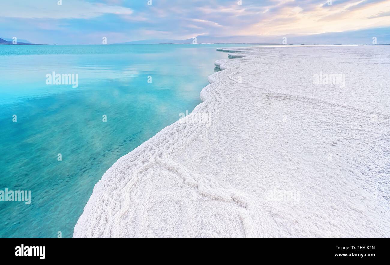 Le soleil du matin brille sur des cristaux de sel blanc, clair vert cyan eau calme près, paysage typique à la plage d'Ein Bokek, Israël Banque D'Images