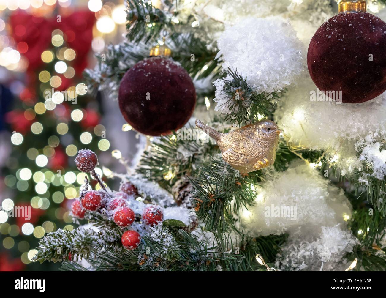 Noël jouet oiseau doré et boules de Noël bordeaux sur le fond du beau bokeh. Banque D'Images
