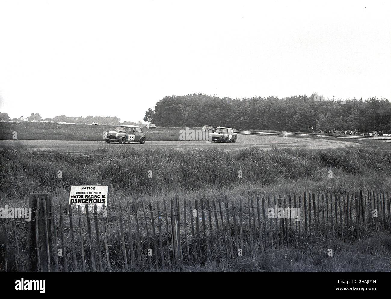 1960s, historique, sport automobile, courses automobiles, Angleterre,ROYAUME-UNI.Loin de la piste, un petit avertissement sur l'herbe par une courte clôture en bois dit, Motor Racing est DANGEREUX. Banque D'Images