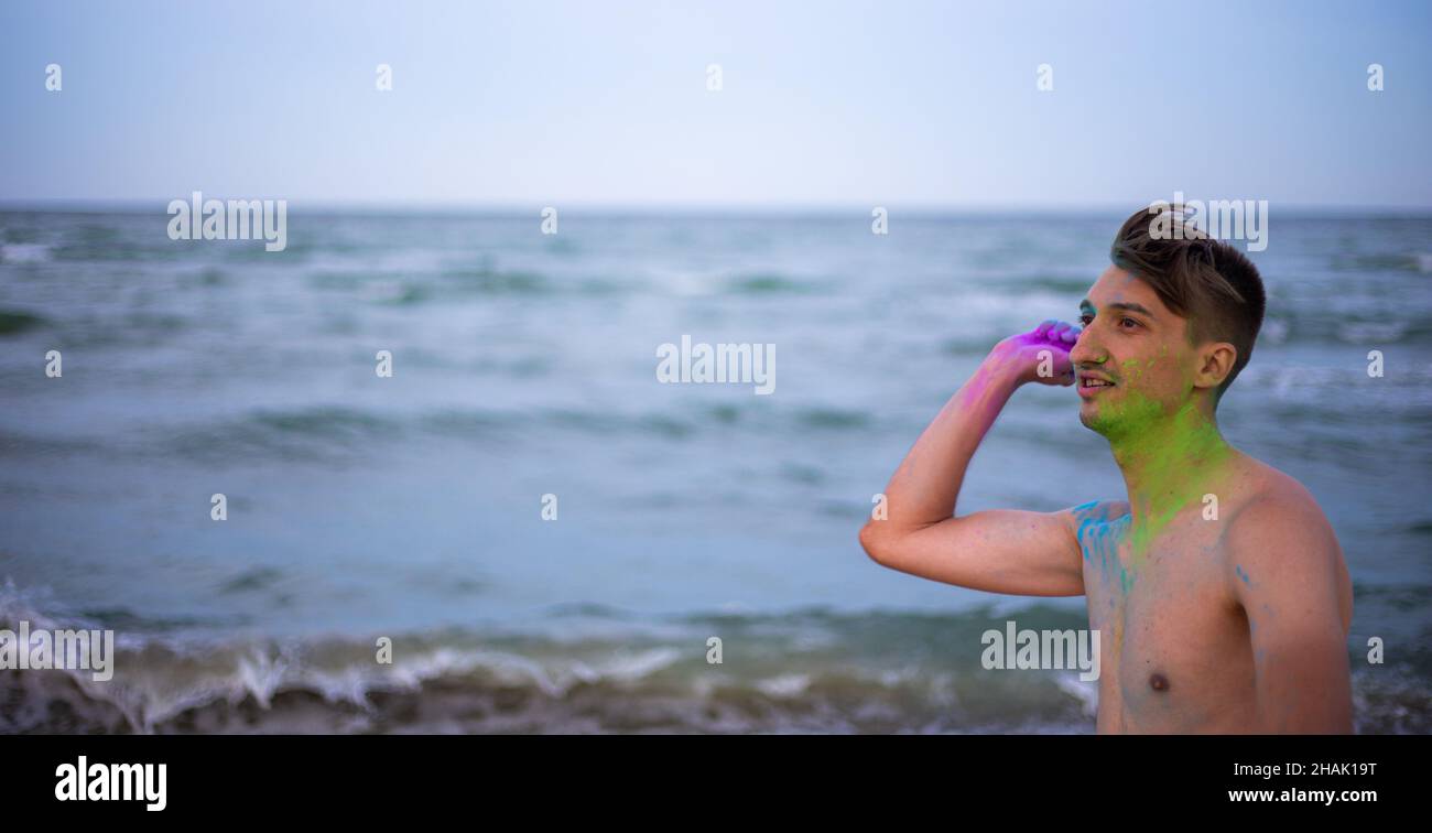 Un jeune homme jette de la poudre de couleur sur le fond de la mer Banque D'Images