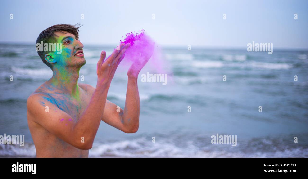Un jeune homme jette de la poudre de couleur sur le fond de la mer Banque D'Images