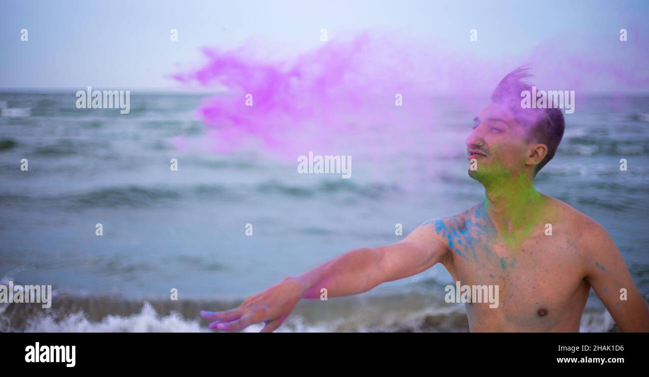 Un jeune homme jette de la poudre de couleur sur le fond de la mer Banque D'Images