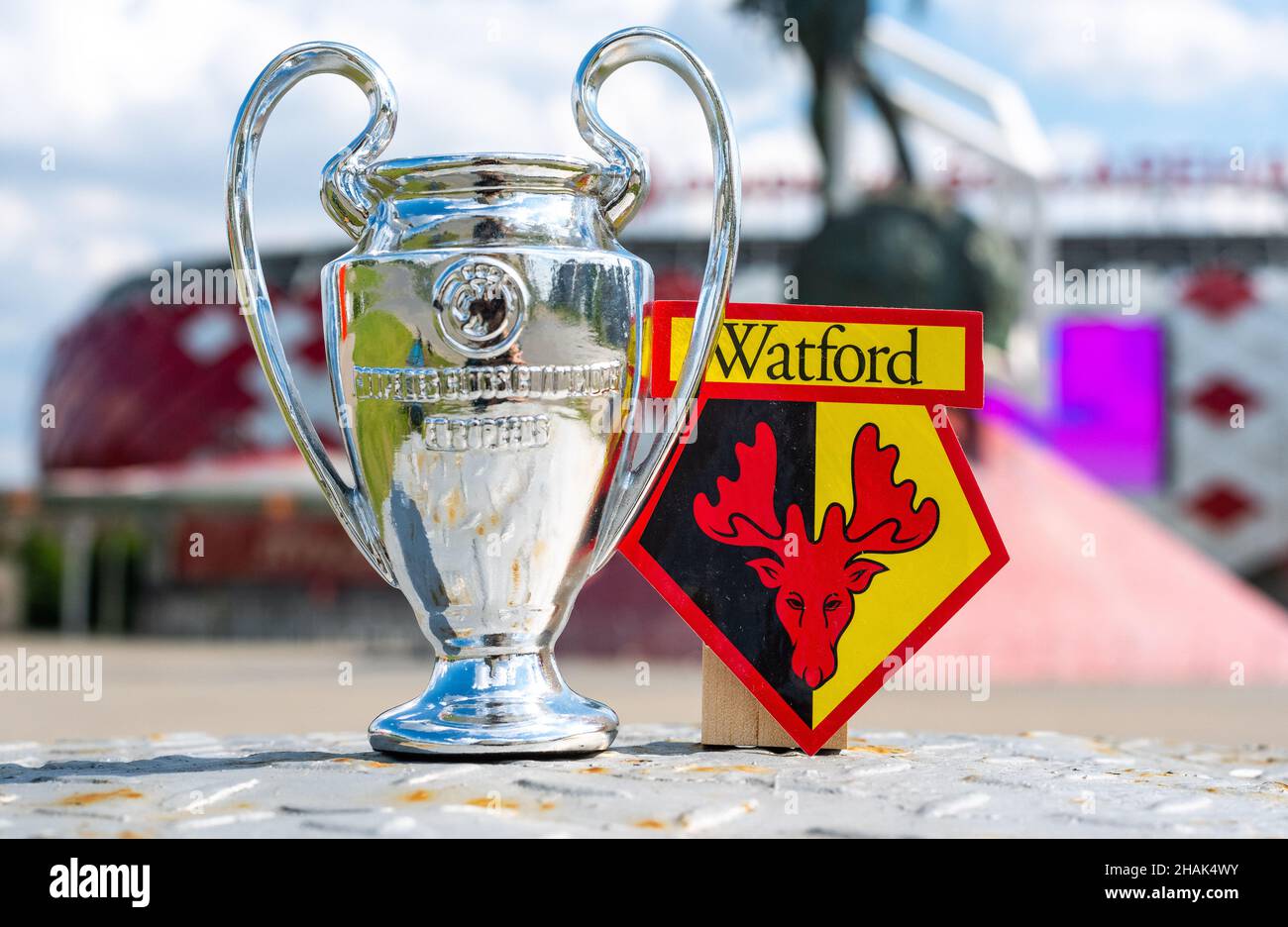 14 juin 2021, Watford, Royaume-Uni.Watford F.C.Emblème du club de football et coupe de la Ligue des champions de l'UEFA sur fond de stade moderne. Banque D'Images