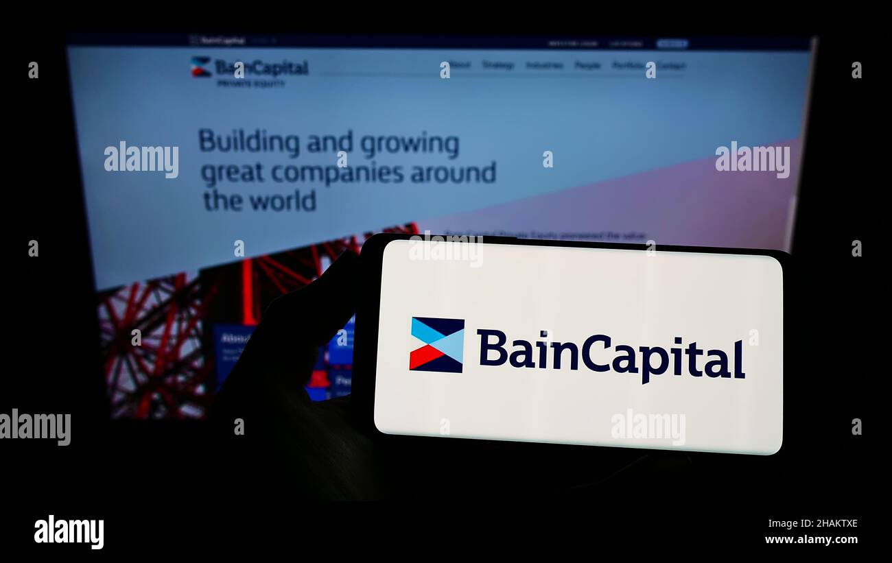 Personne tenant un smartphone avec le logo de la société d'investissement américaine bain Capital L.P. sur l'écran devant le site Web.Mise au point sur l'affichage du téléphone. Banque D'Images