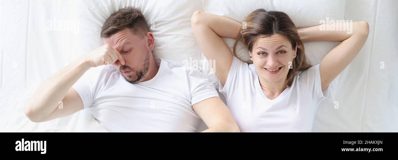 Couple marié allongé dans le lit. Homme couvrant son nez avec sa main Banque D'Images