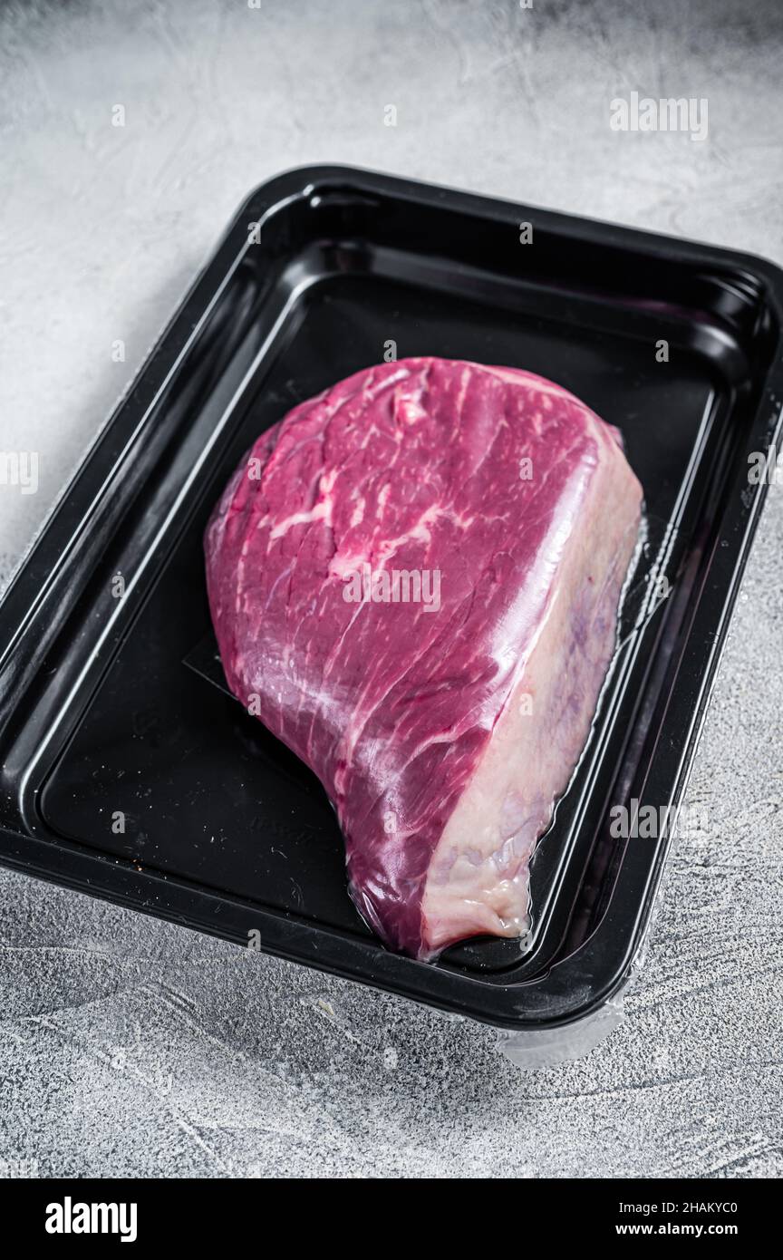 Steak de bœuf cru ou steak de viande de bœuf au sirloin dans un emballage sous vide. Arrière-plan blanc. Vue de dessus Banque D'Images