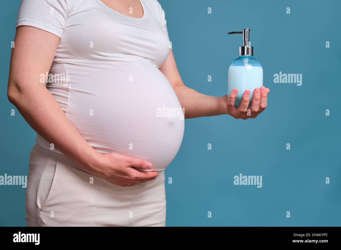 Savon liquide avec distributeur dans les mains de la femme enceinte, prise  en studio sur fond bleu Photo Stock - Alamy