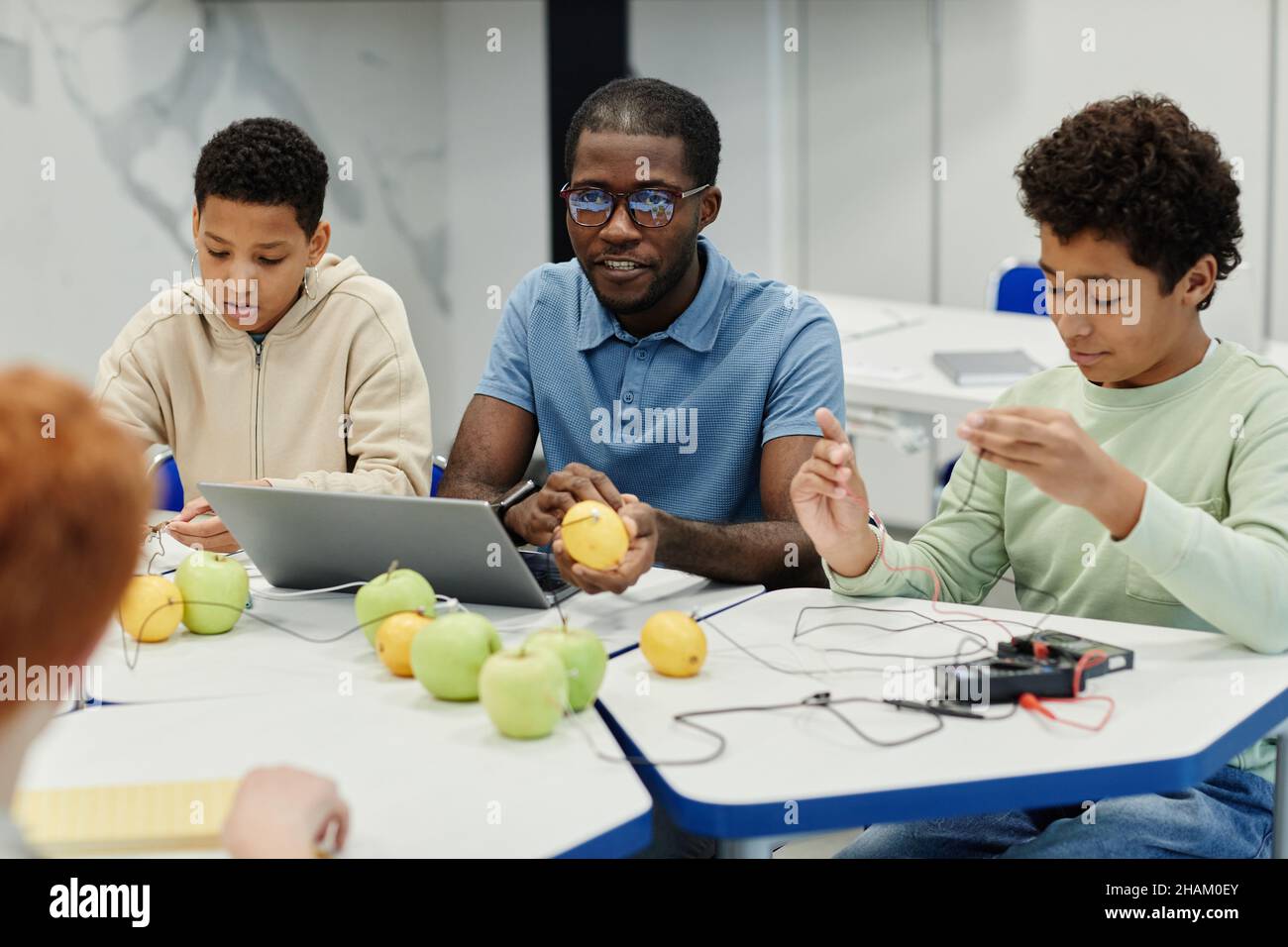 Portrait d'un enseignant afro-américain travaillant sur des expériences scientifiques avec divers groupes d'enfants Banque D'Images