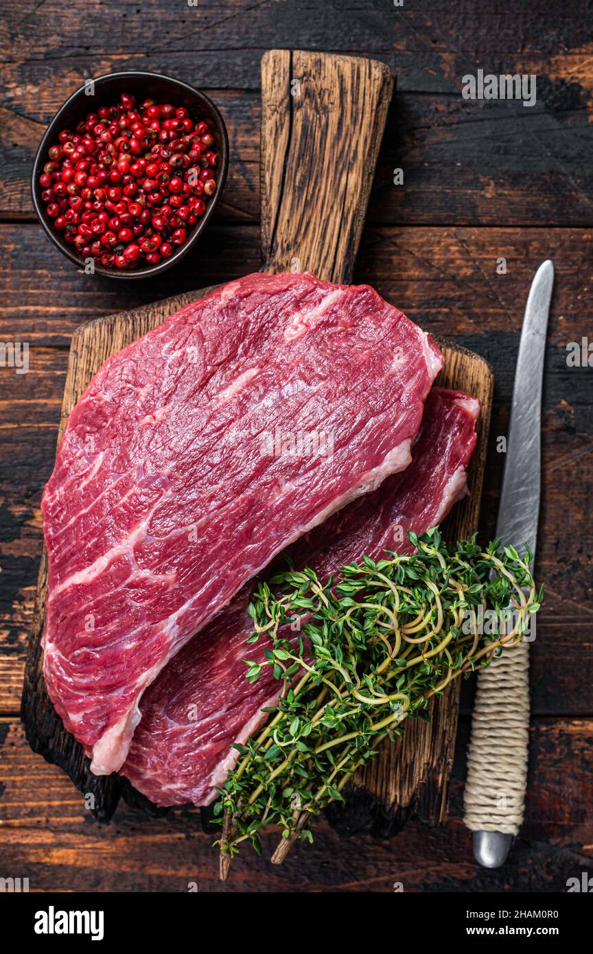 Steak de chapeau de sirloin cru ou steak de Picanha sur une planche de bois au thym. Arrière-plan en bois sombre. Vue de dessus Banque D'Images
