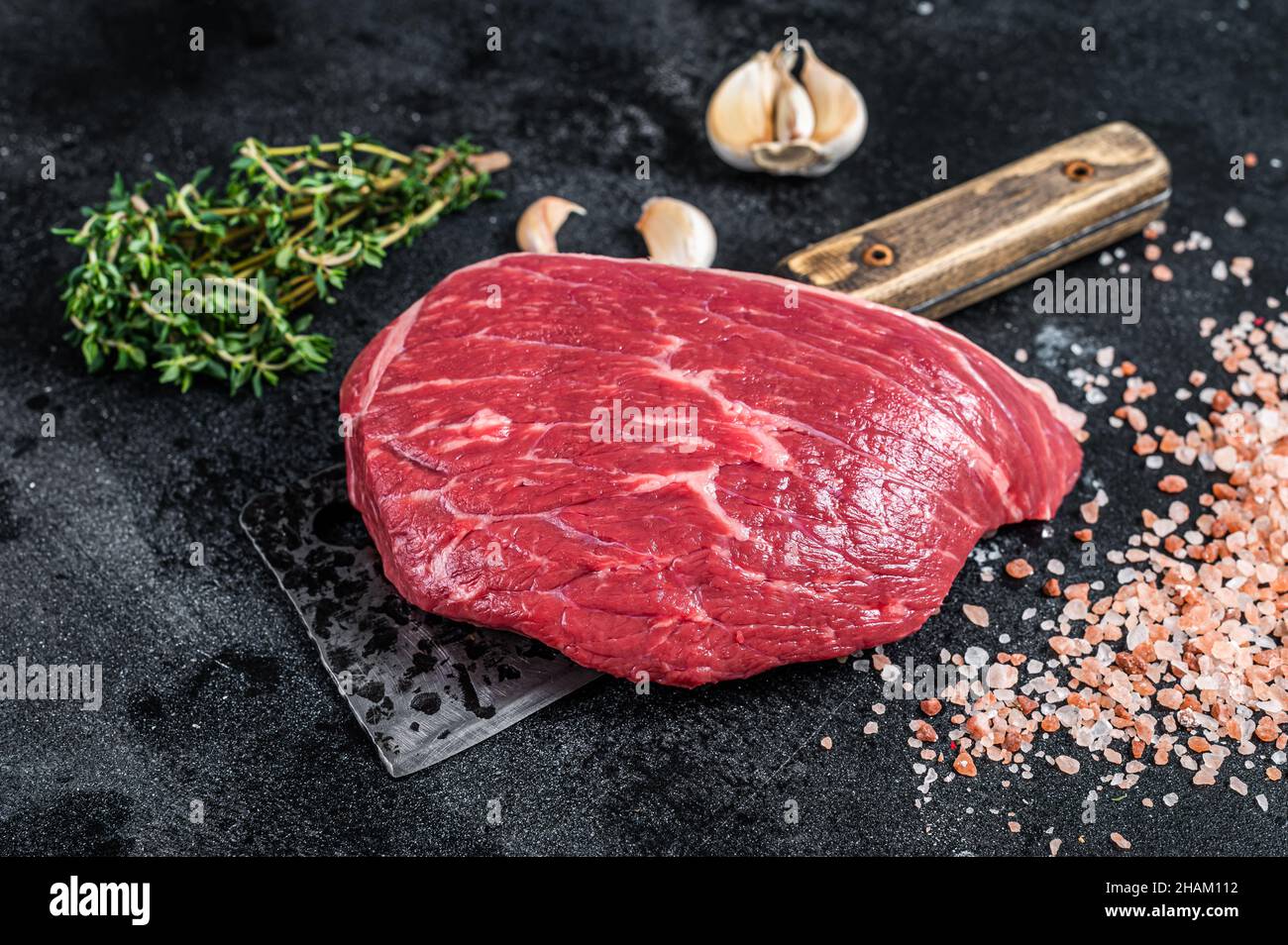 Bœuf cru frais coupé ou steak de chapeau de sirloin sur le couperet de boucher. Arrière-plan noir. Vue de dessus Banque D'Images