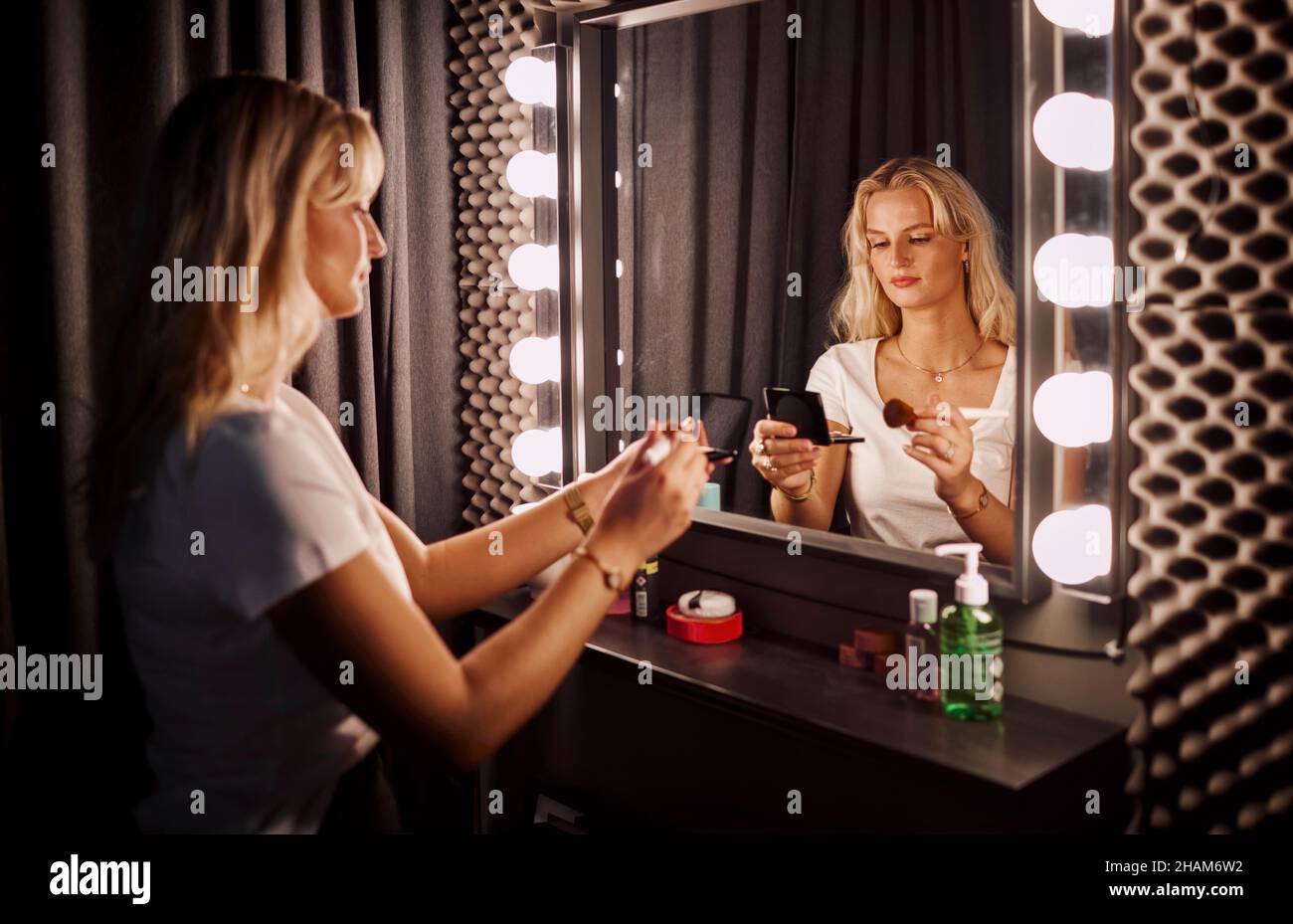 Jeune femme appliquant le maquillage devant le miroir Banque D'Images