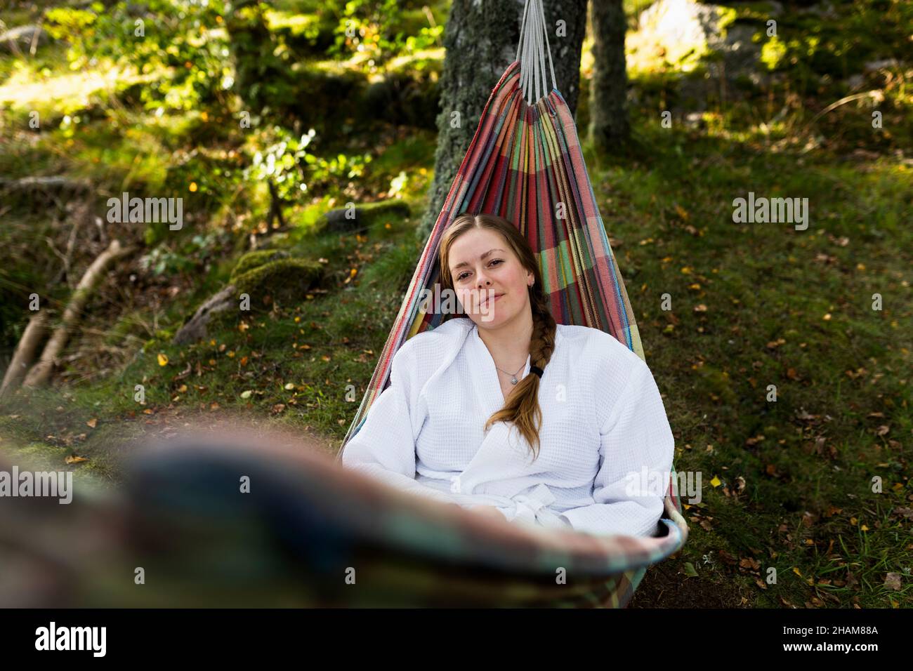 Jeune femme en peignoir de détente dans hamac Banque D'Images