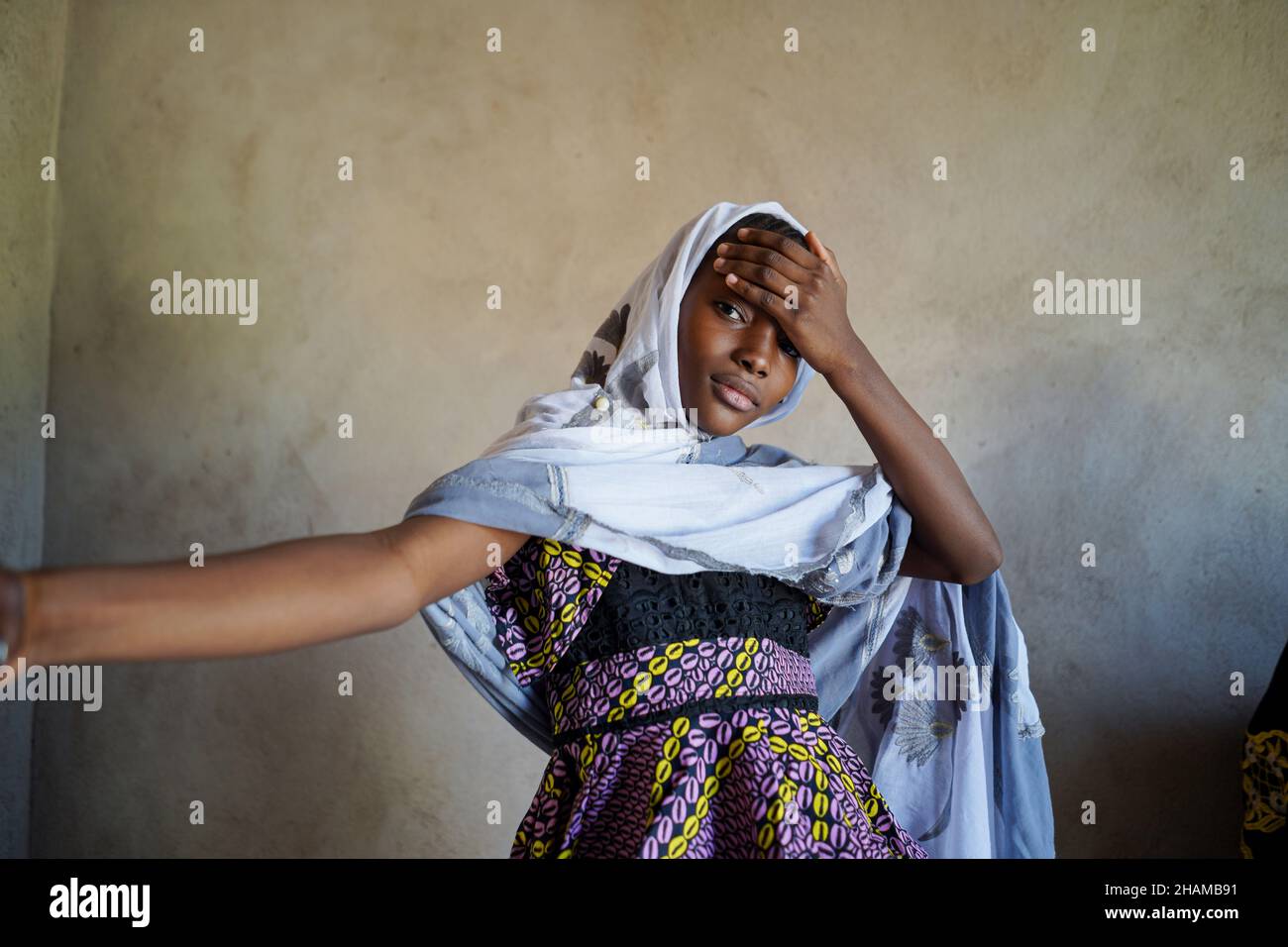 Magnifique Mali African Girl Portrait.Belle femme adolescente noire avec main sur le front avec arrière-plan de mur rugueux Banque D'Images