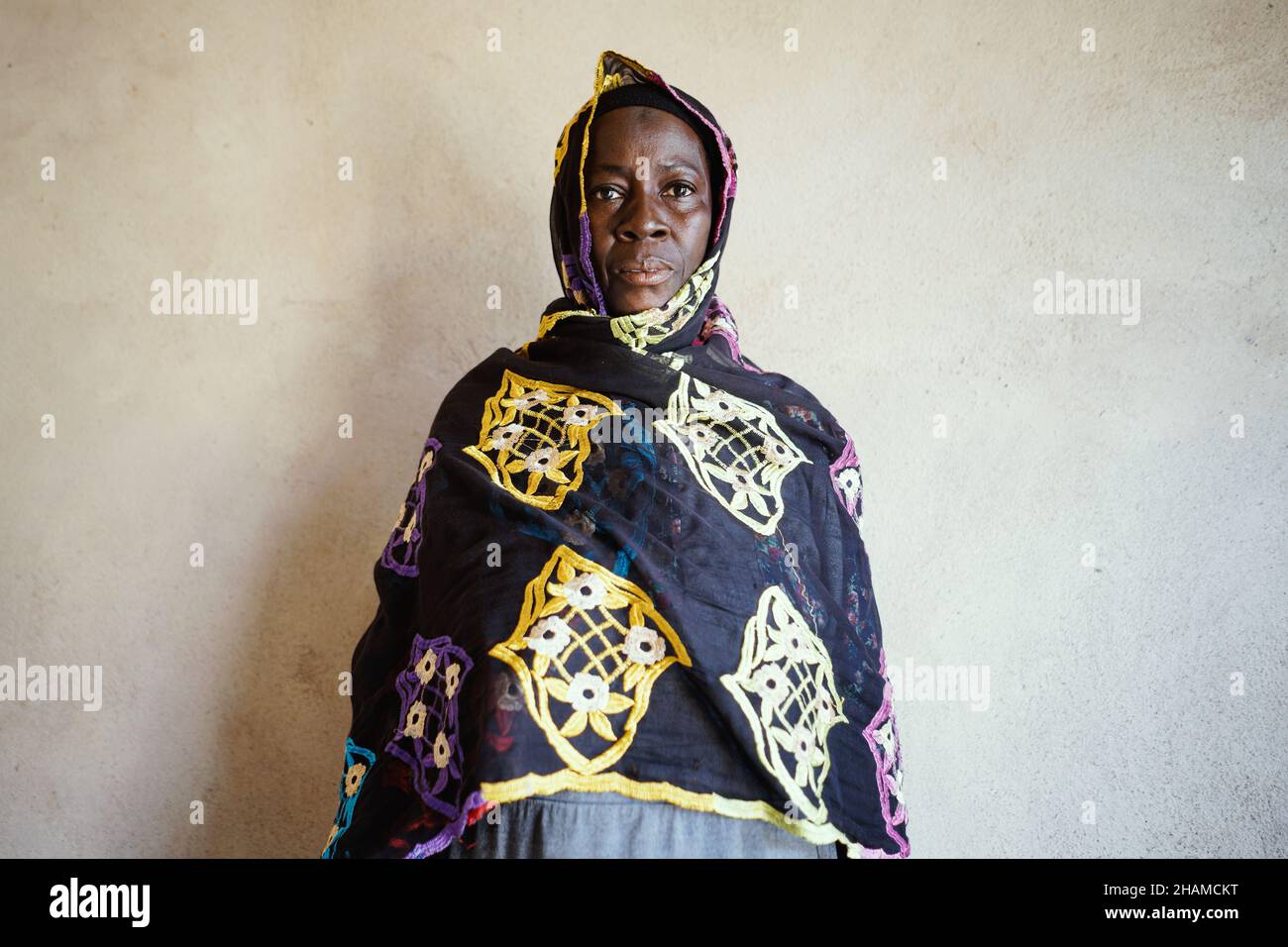 La femme africaine d'origine ethnique se trouve près d'un mur blanc isolé dans des vêtements traditionnels Banque D'Images