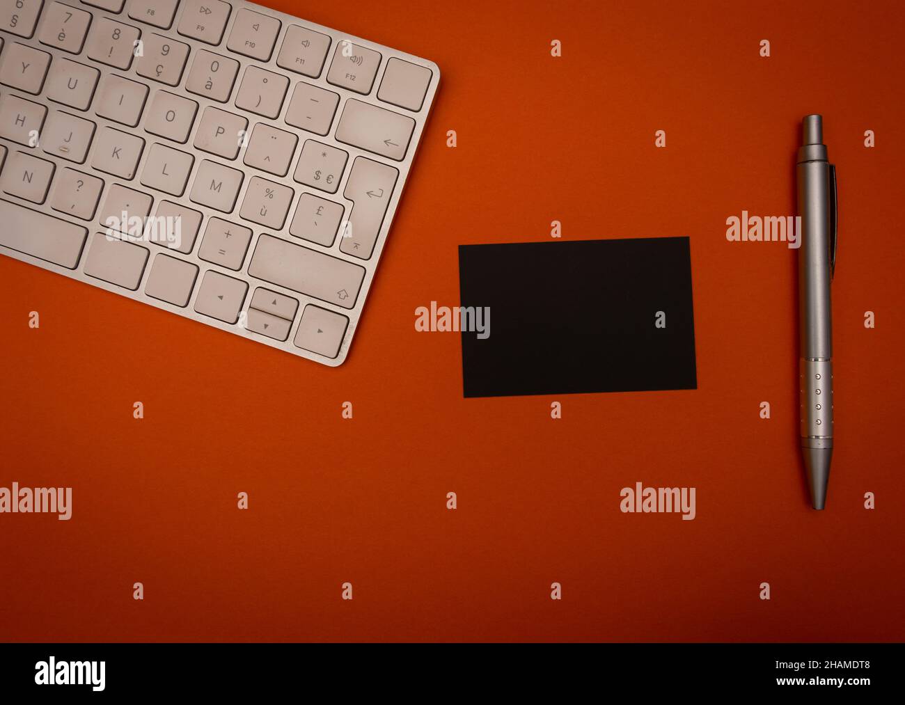 Carte de visite maquette noire pour marquage sur fond orange avec clavier d'ordinateur et stylet Banque D'Images