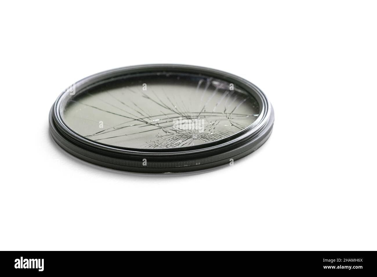 Gros plan en studio grand angle avec filtre polariseur circulaire noir en verre fissuré, isolé sur fond blanc.Concept de dommages de l'équipement photo Banque D'Images