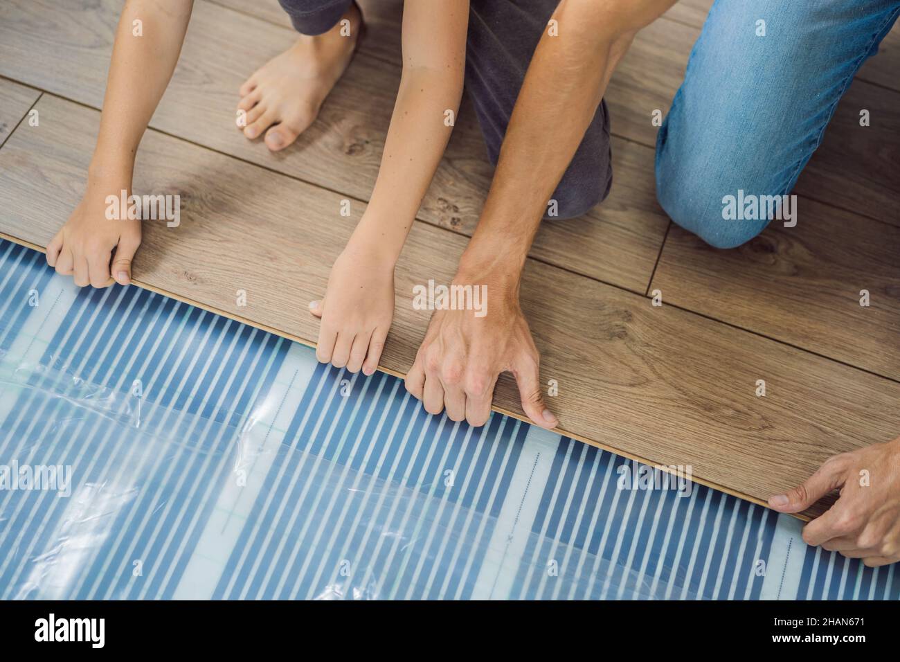 Père et fils installant un nouveau parquet stratifié en bois sur un — free download