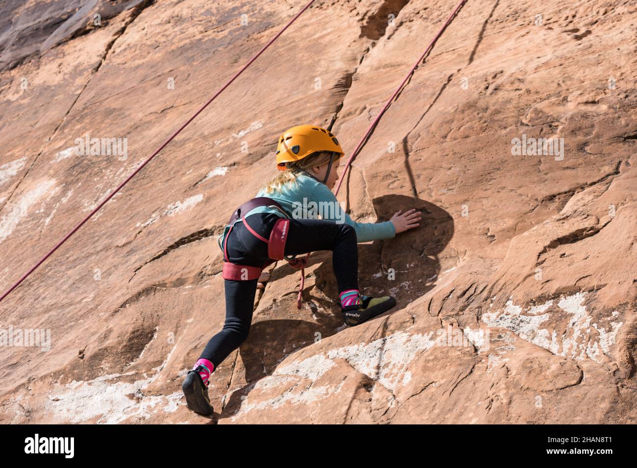 Une jeune fille de sept ans qui apprend à grimper dans la zone d'escalade de Wall Street près de Moab, Utah. Banque D'Images