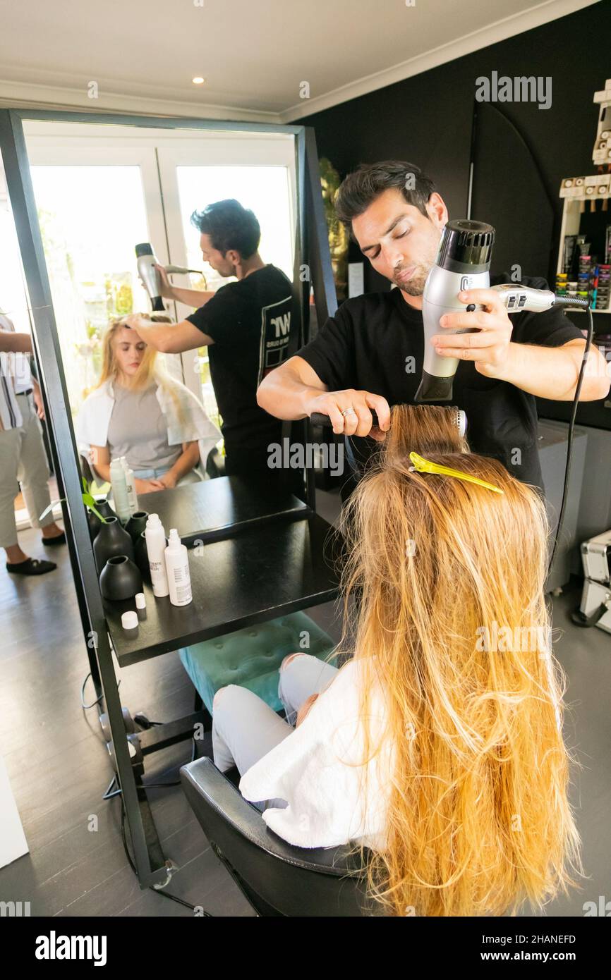 CAPE TOWN, AFRIQUE DU SUD - 26 octobre 2021 : la célèbre coiffeuse Marios Atzemoglou coiffant les cheveux d'une mannequin féminine Banque D'Images