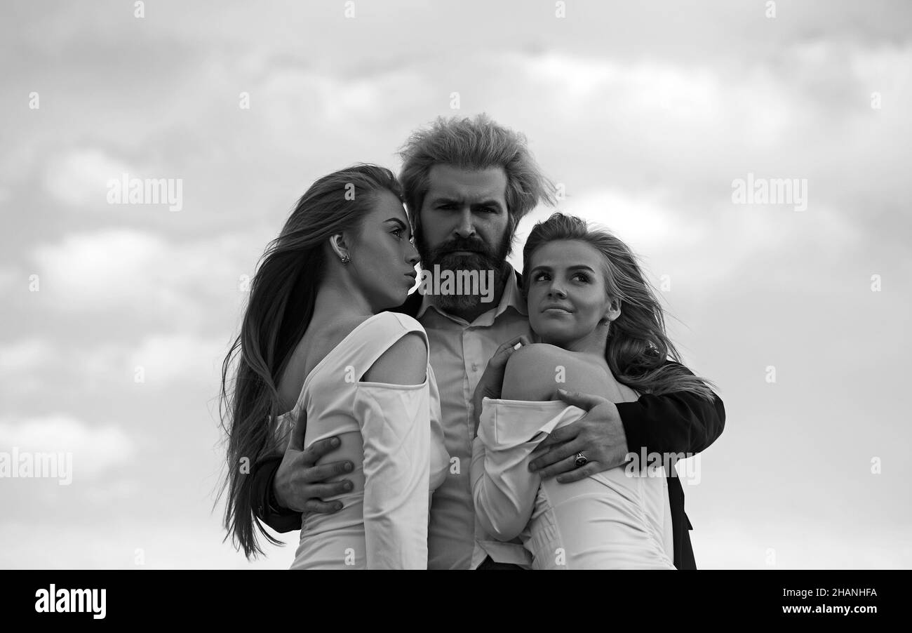 Photo de mode de beau homme et deux femmes. Fond ciel. Banque D'Images