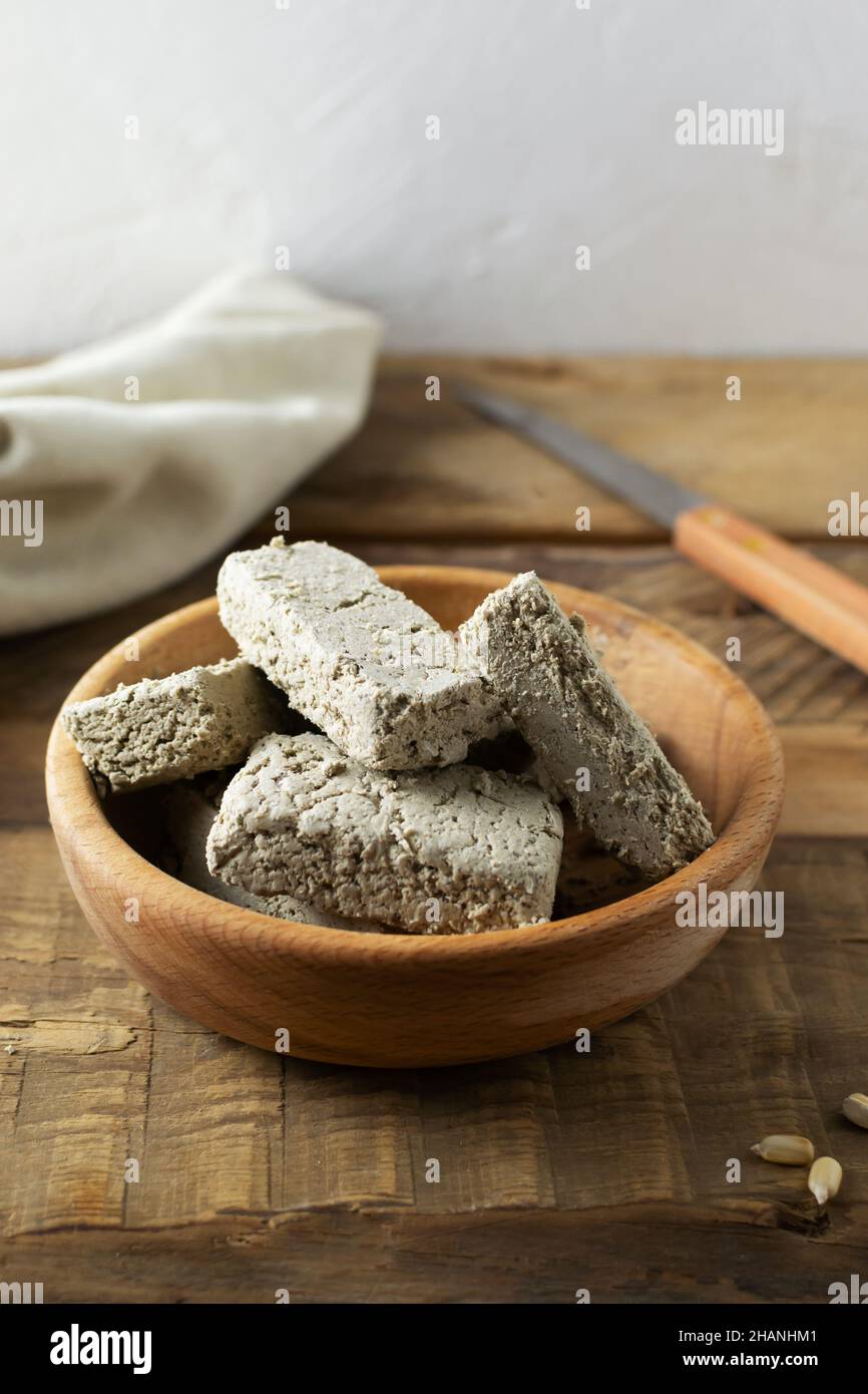 Halva de tournesol dans un bol en bois avec un vieux couteau et un psaume sur une table en bois.Style rustique.Bonbons traditionnels.Plats végétariens.Copier l'espace.Verti Banque D'Images