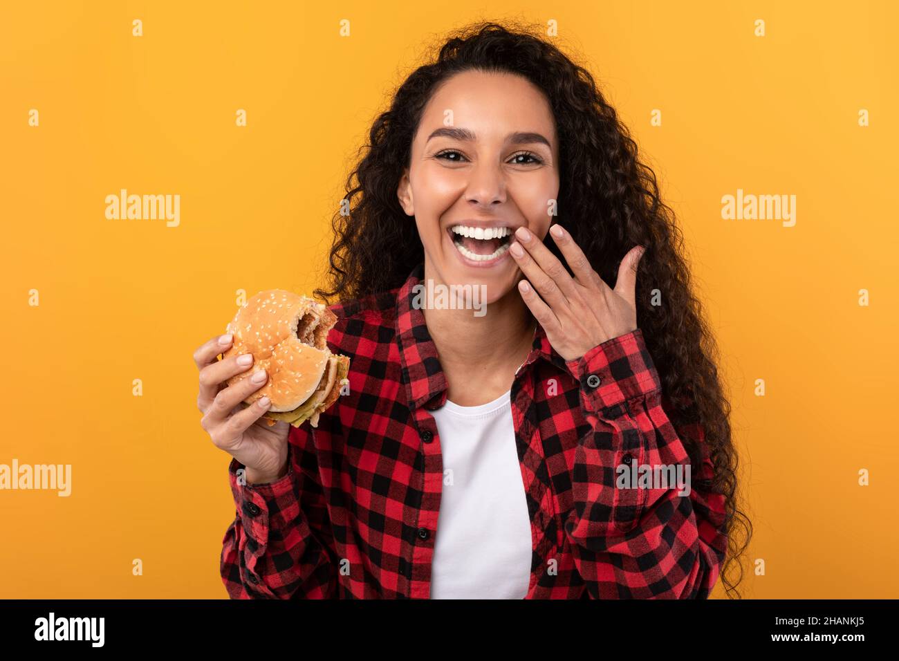 Happy Raughing Lady Eating Burger au Studio Banque D'Images