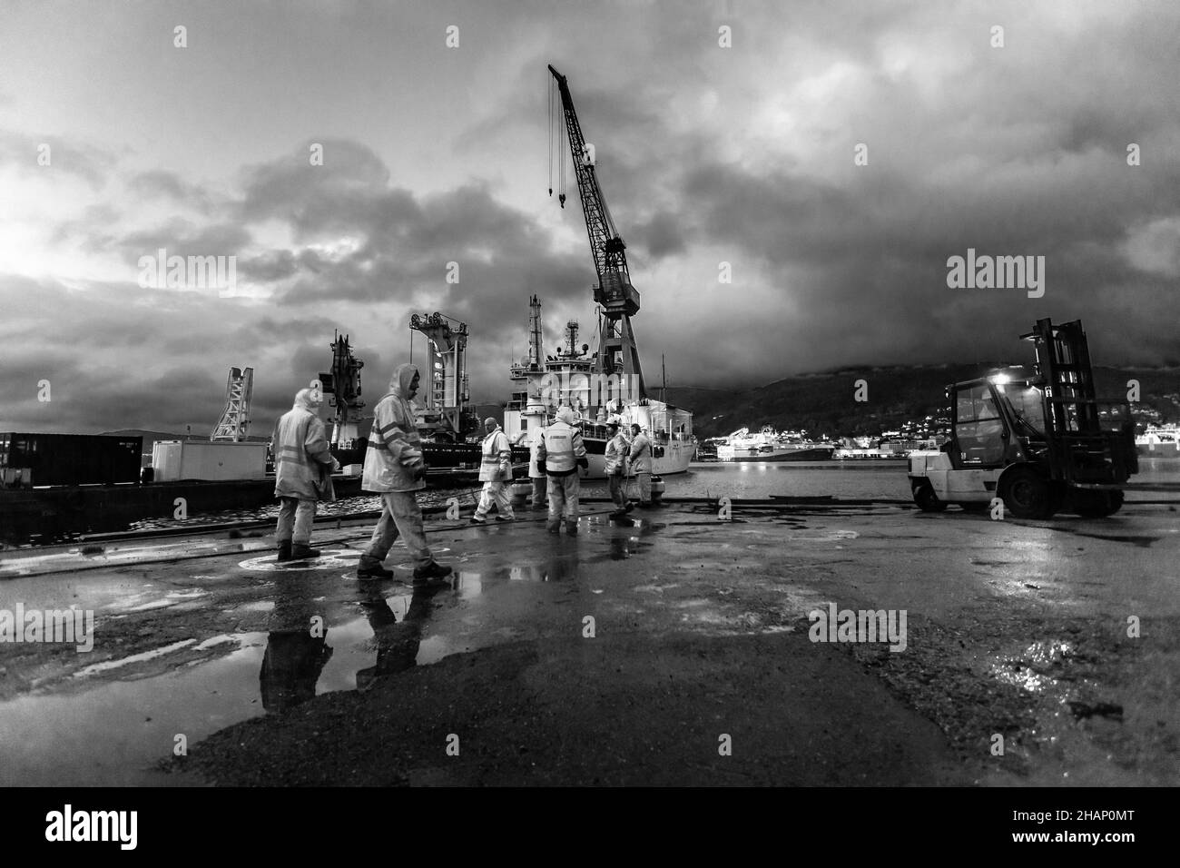 Travailleurs à un quai sec de l'ancien chantier naval de BMV à Laksevaag, près du port de Bergen, en Norvège.Navire prêt à quitter le quai.Le yacht royal en arrière-plan, p Banque D'Images