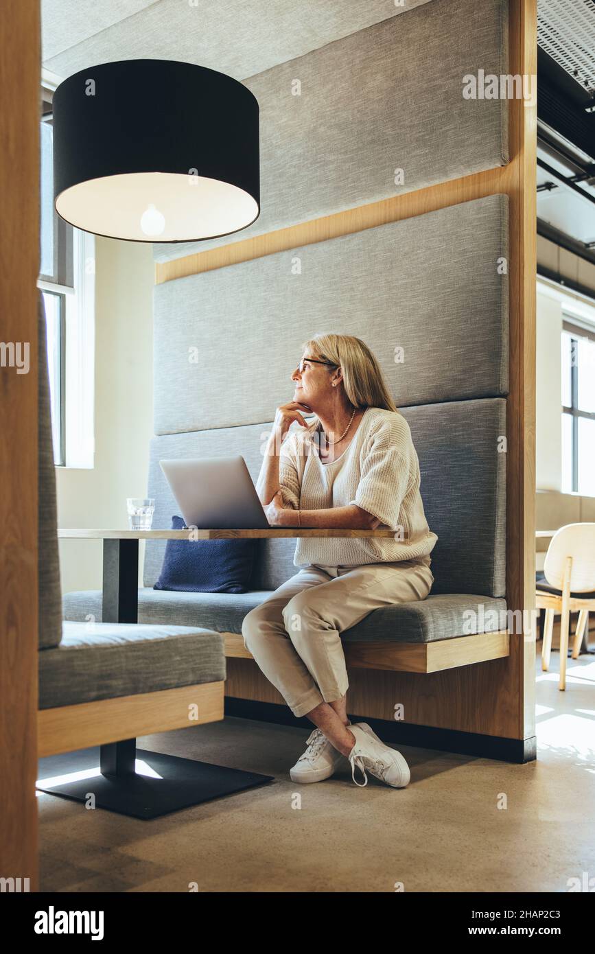 Femme d'affaires mûre contemplative travaillant dans un espace de travail moderne.Femme d'affaires mûre pensant à de nouvelles idées d'affaires.Entrepreneur féminin expérimenté Banque D'Images