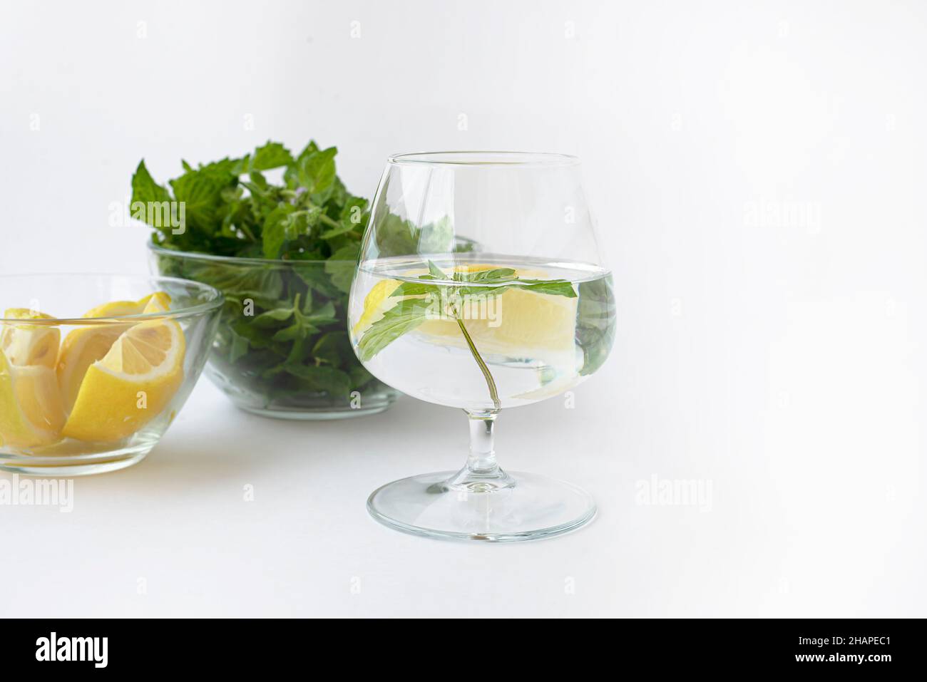 Trois bols en verre.Un bol de feuilles de menthe.Un bol de quartiers de citron et un verre d'eau de détox. Banque D'Images