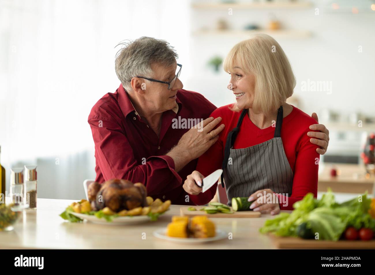 Couple de personnes âgées aimant se regardant les unes les autres tout en préparant la dinde rôtie traditionnelle pour le dîner de Noël à la maison Banque D'Images