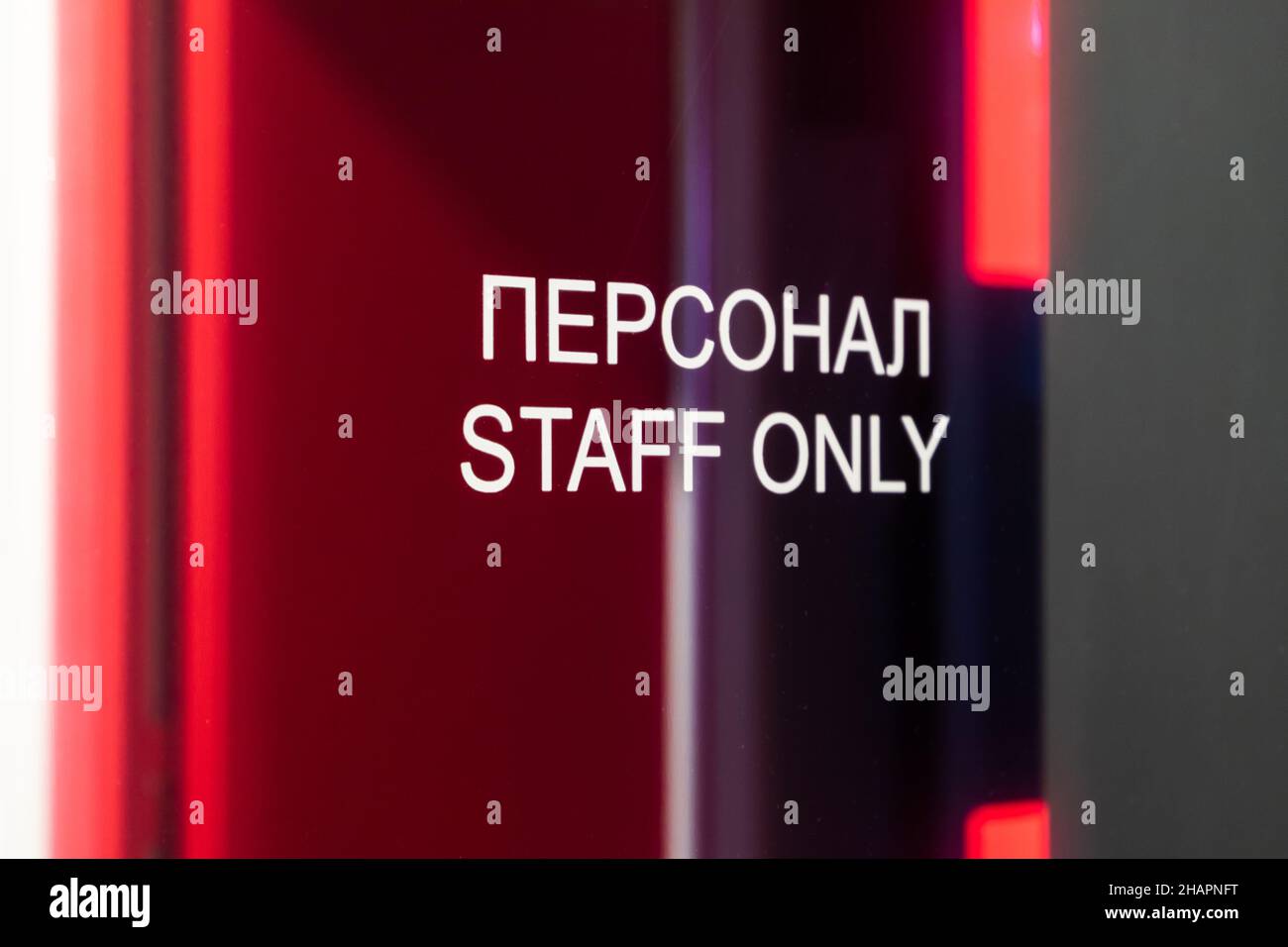 Personnel seulement, texte blanc en anglais et russe est sur la porte vitrée avec des reflets colorés Banque D'Images
