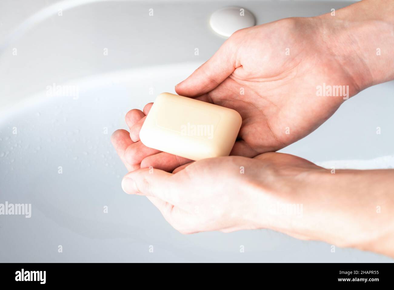Savon dans les mains d'un homme contre le fond du lavabo dans la salle de bains.Concept d'hygiène pour la protection contre l'infection à coronavirus Banque D'Images