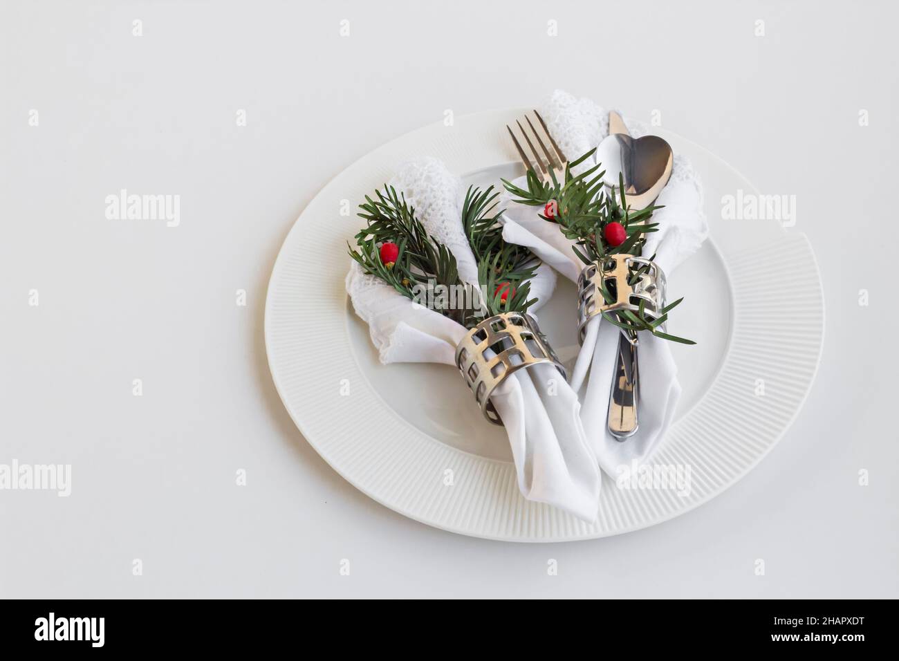 Menu de Noël ou du nouvel an avec des serviettes en tissu blanc, des ronds de serviettes et des couverts dans une assiette sur blanc Banque D'Images
