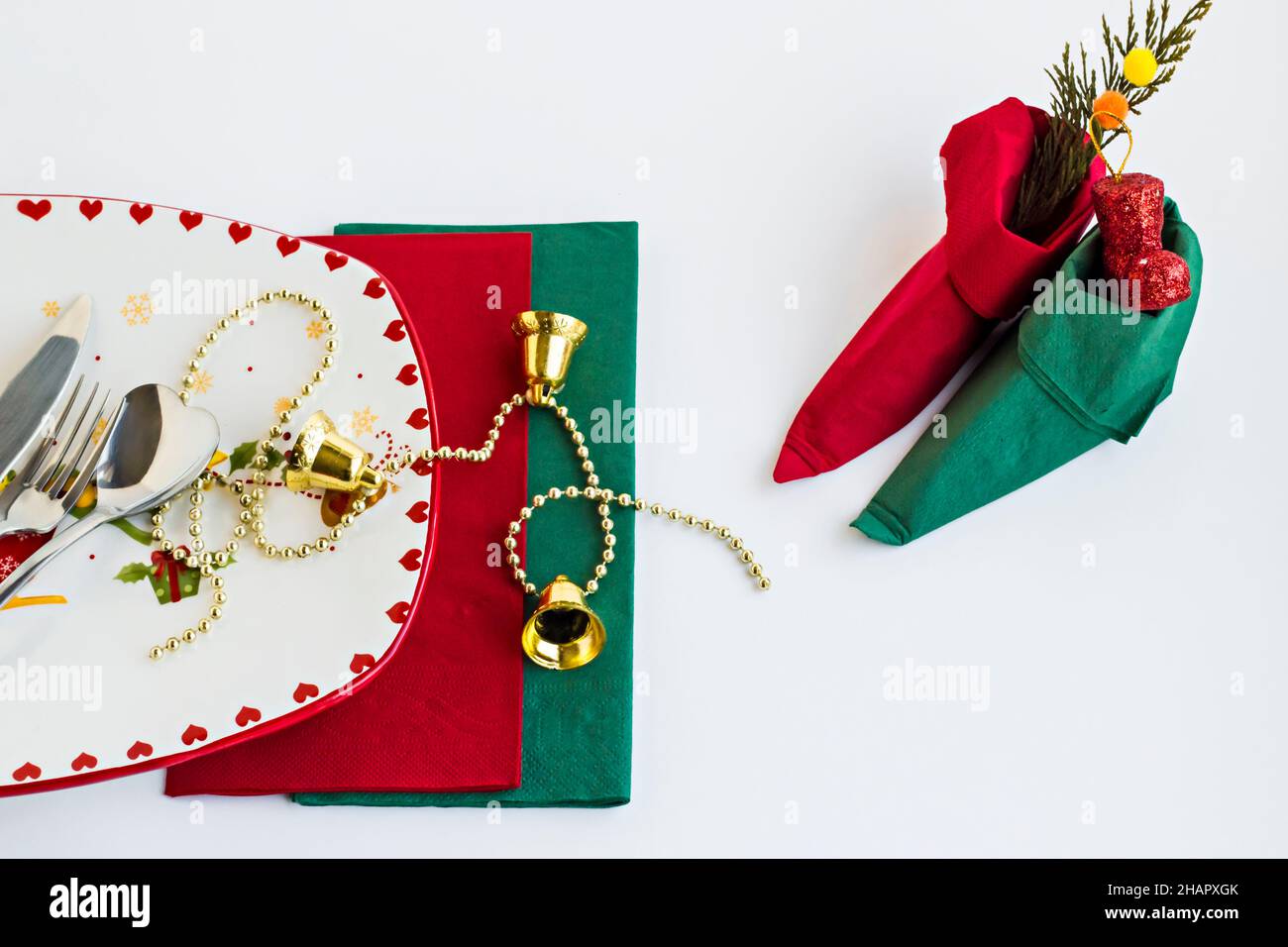 Assiette de Noël élégante et vide et couverts sur une surface blanche avec des serviettes vertes et rouges, plié une petite chaussure d'elfe Banque D'Images