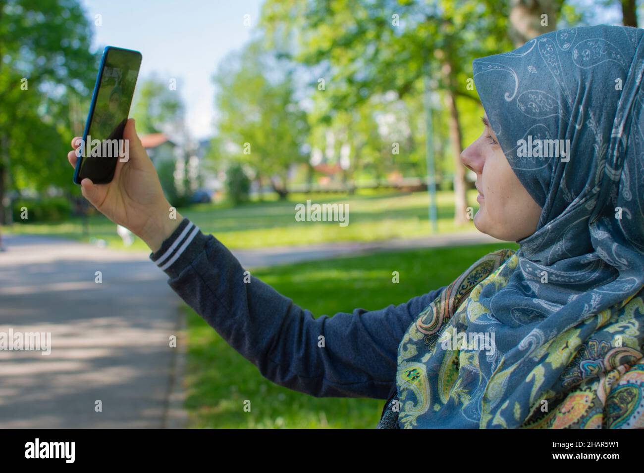 Femme enceinte musulmane prenant selfie dans le parc avec un smartphone Banque D'Images