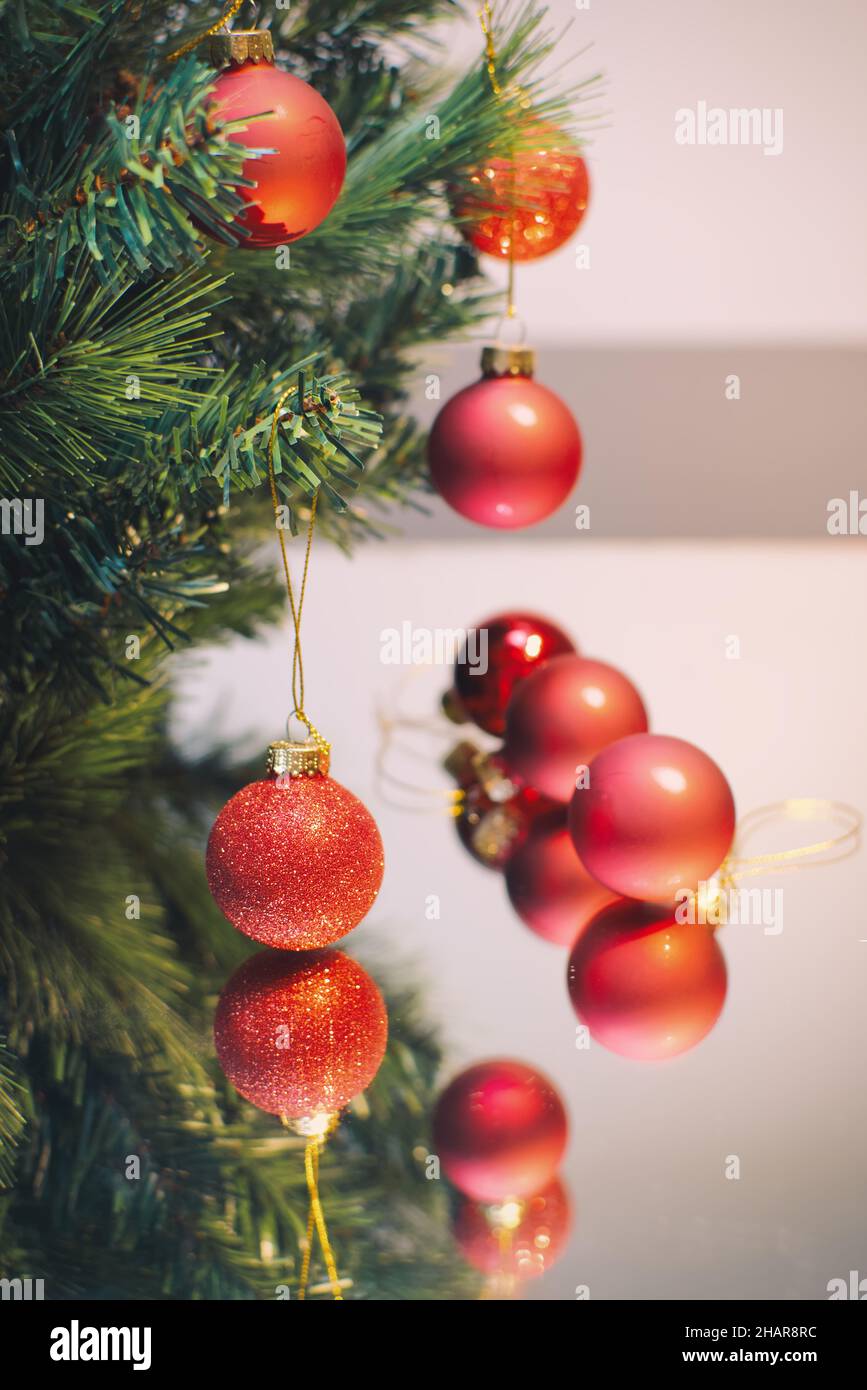 Boules décoratives rouges de Noël accrochées à l'arbre reflétées dans la surface en verre Banque D'Images