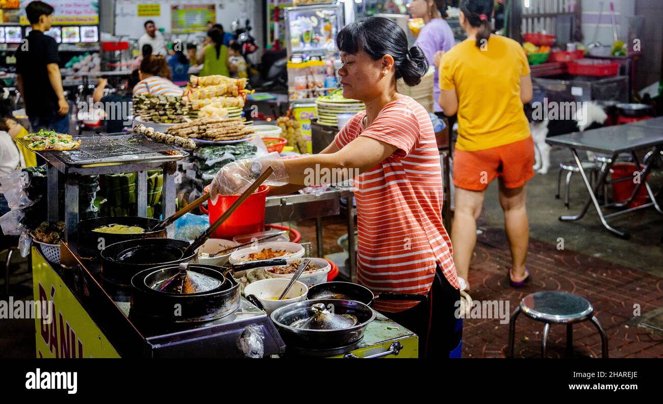 Plusieurs femmes vietnamiennes cuisent de la nourriture de rue sur leurs chariots. Banque D'Images