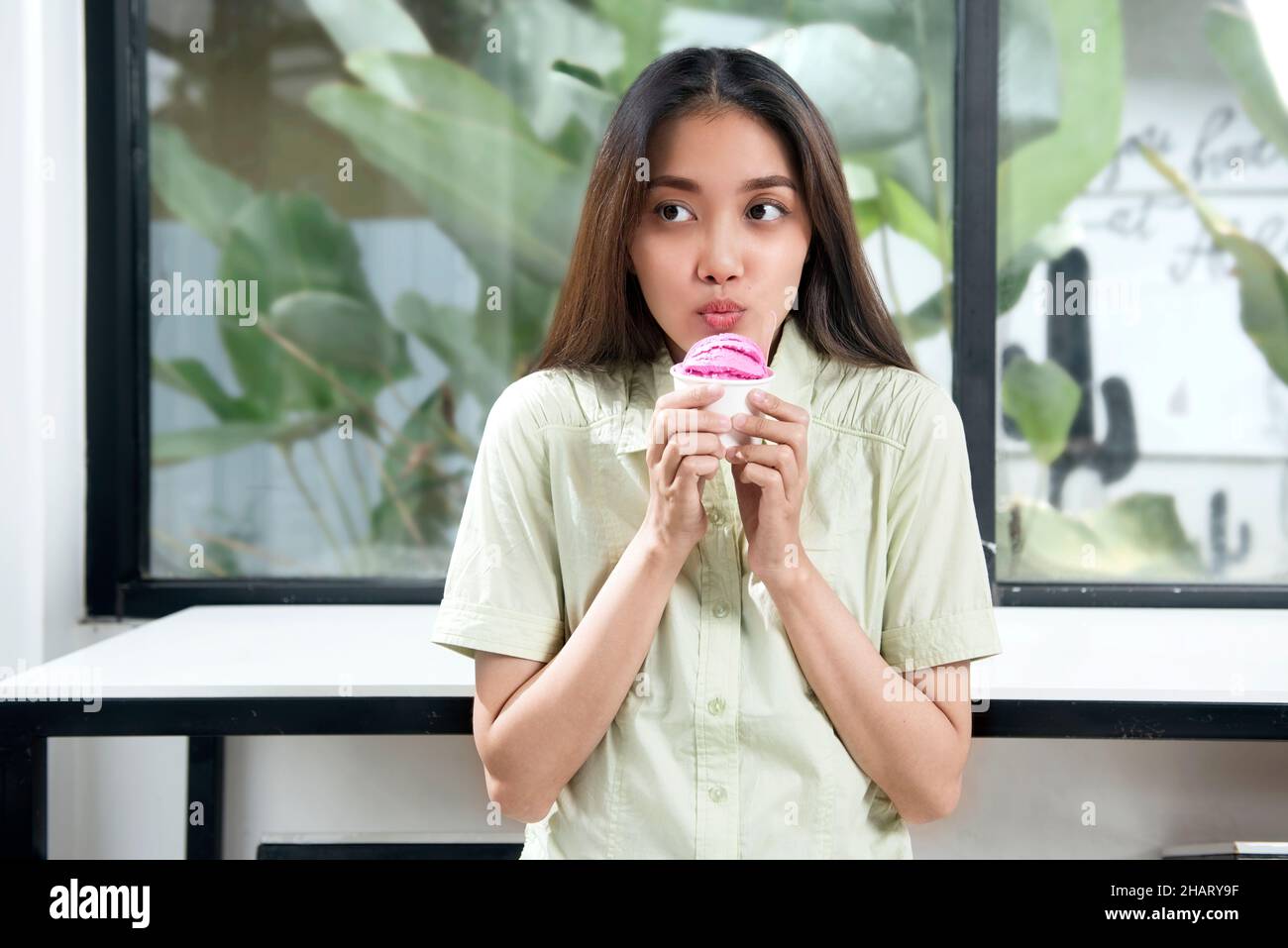 Femme asiatique tenant une tasse de glace à la fraise dans le café Banque D'Images