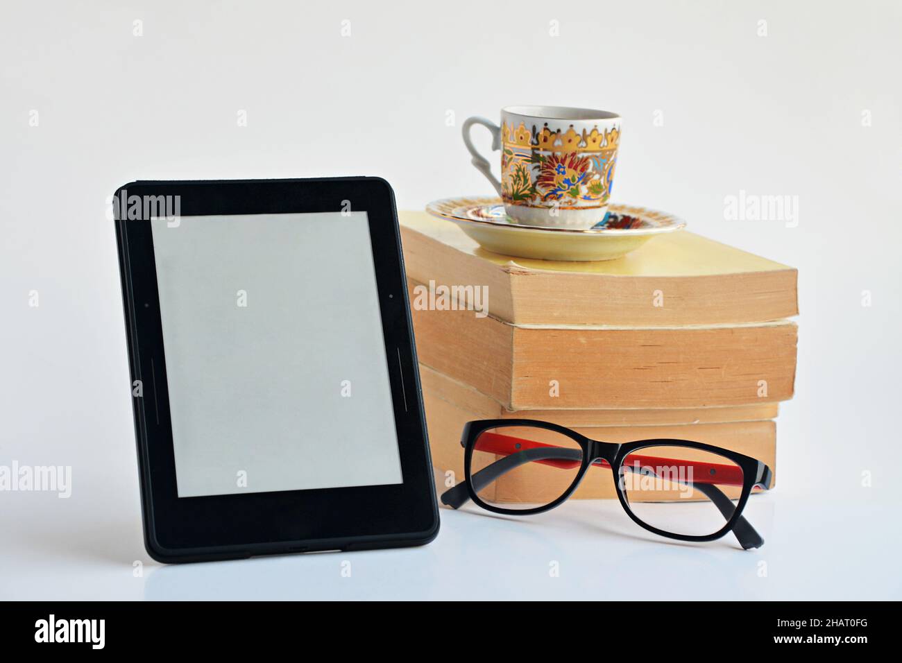 Lecteur de livres électroniques numériques avec un écran vierge sur fond blanc avec des lunettes, des livres en papier et une tasse à café.gros plan pris. Banque D'Images