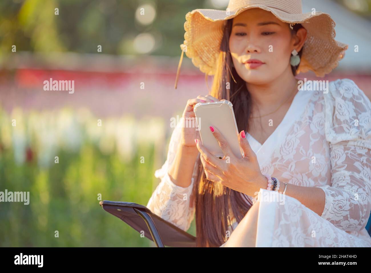 Concentrez-vous sur le téléphone.Une femme asiatique heureuse s'assoit dans la ferme de fleurs en plein air et chitchat sur l'application de rencontres en ligne dans le téléphone mobile.Rencontres en ligne des femmes via vidéo ca Banque D'Images
