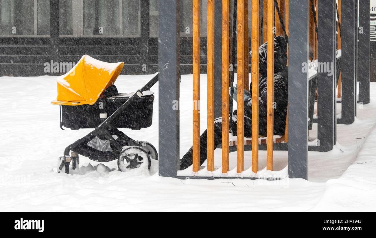 Parent avec poussette et nouveau-né marchant dans le parc de la ville pendant la neige hivernale Banque D'Images
