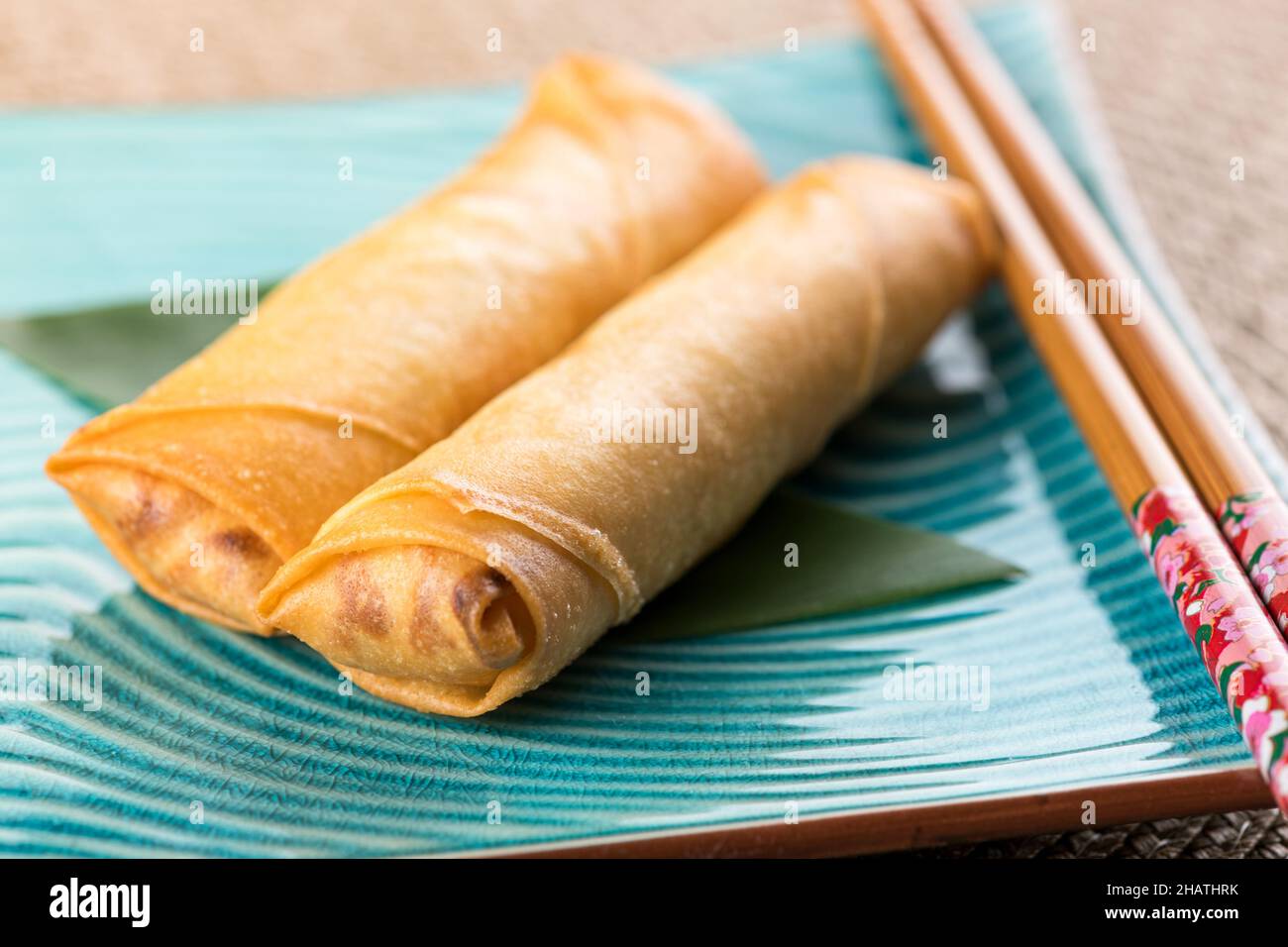 Au-dessus de délicieux rouleaux de printemps servis sur une plaque en céramique bleue avec des baguettes sur une table légère Banque D'Images