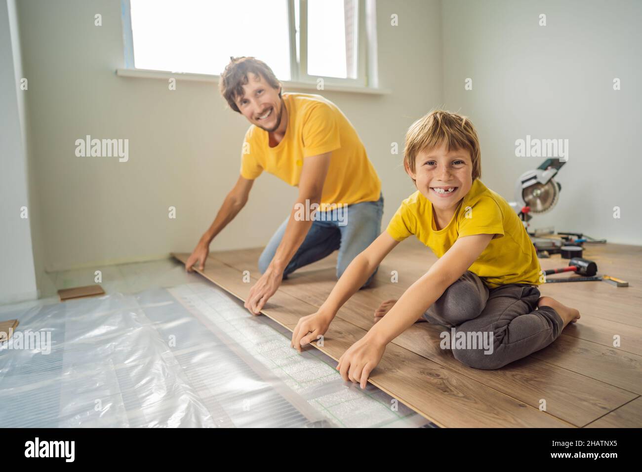 Père et fils installant un nouveau parquet stratifié en bois sur un — free download