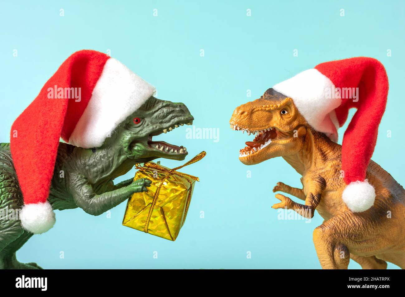 Deux dinosaures Rex en rouge chapeau de Père Noël tient la boîte cadeau dorée dans ses pattes sur fond rose carte de vacances Art de la Saint-Sylvestre ou de la Saint-Sylvestre Creative Banque D'Images