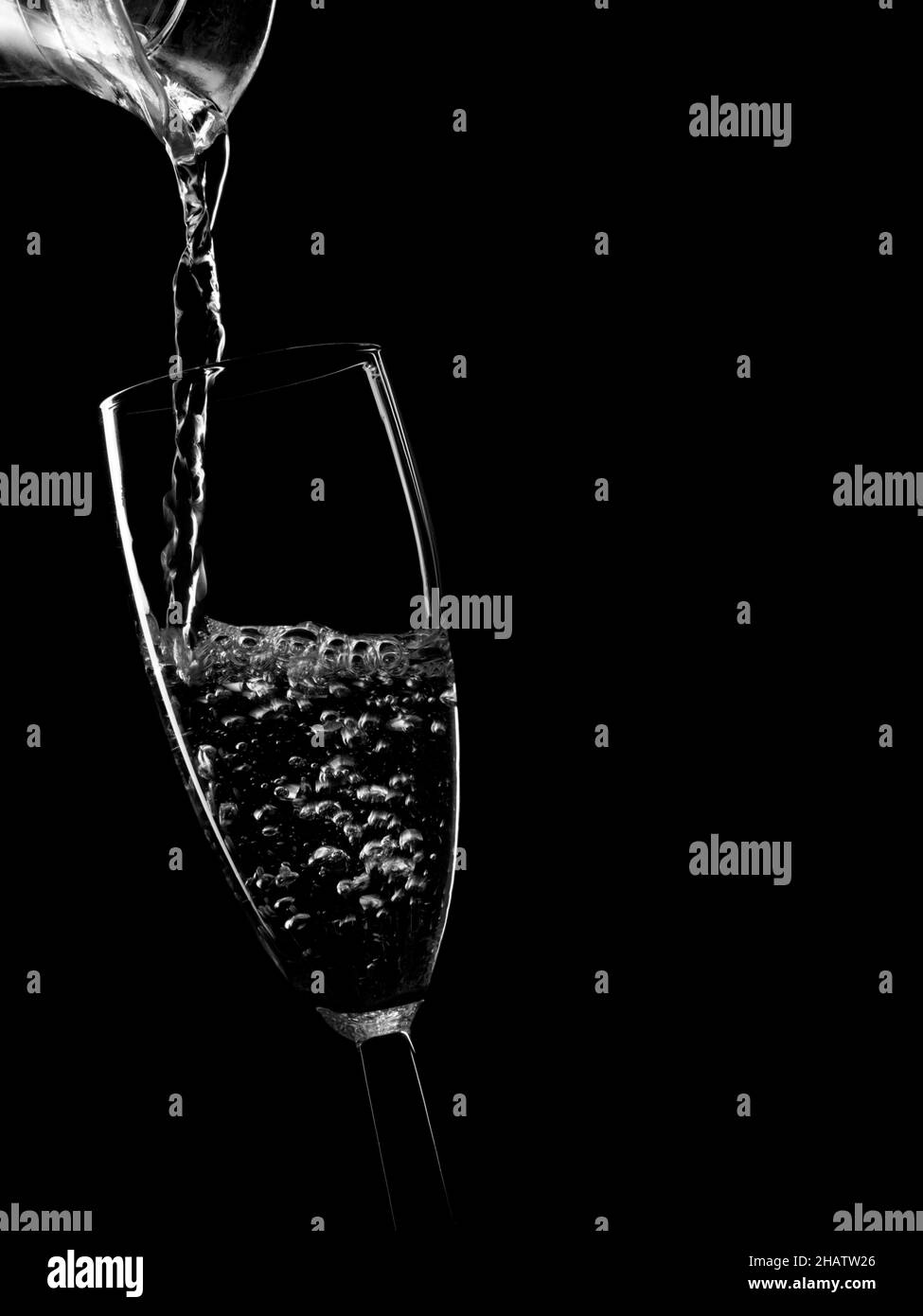 Verser de l'eau, une boisson transparente dans un verre, monochrome. Banque D'Images