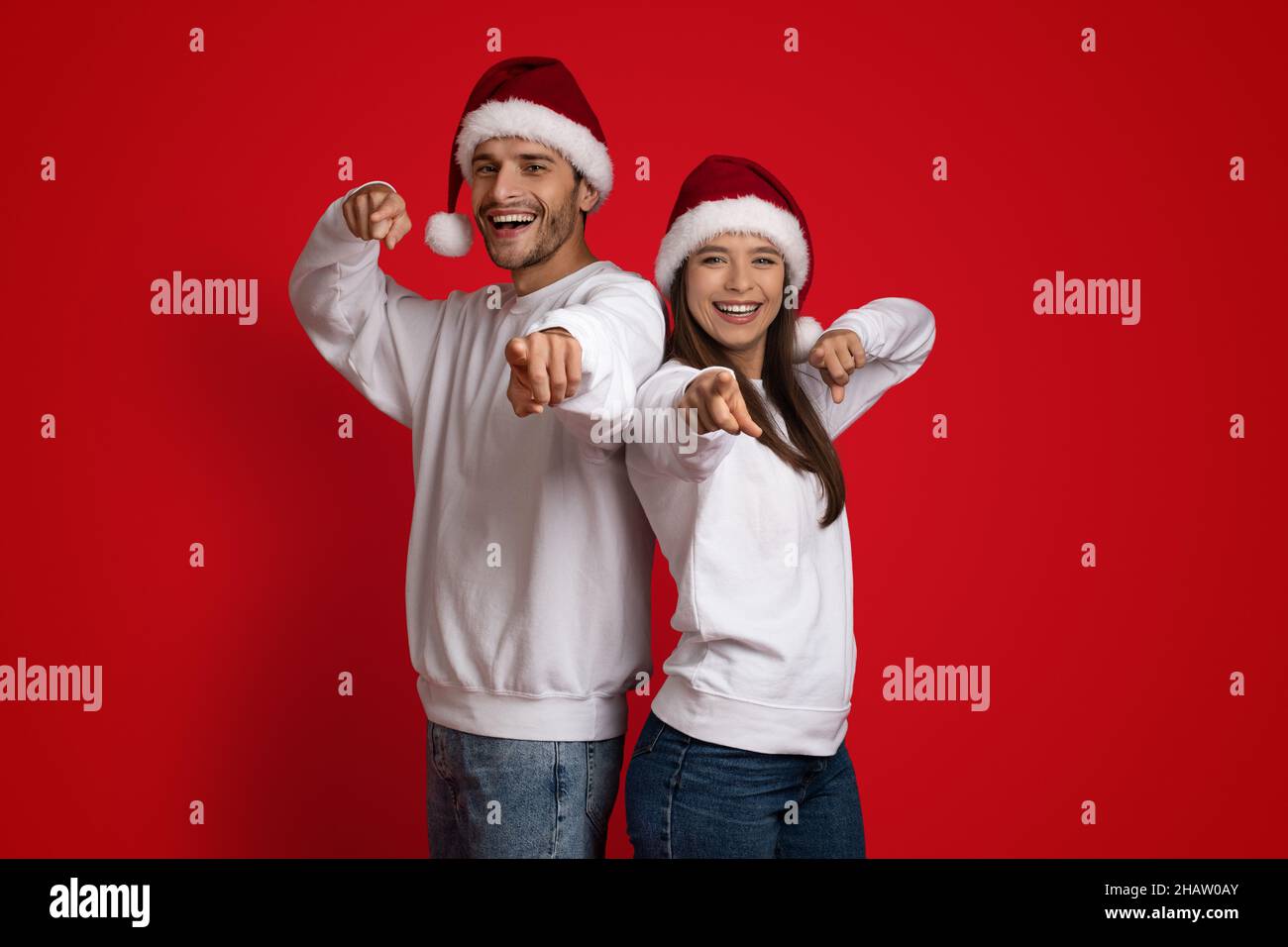 Nous vous choisissons.Couple gai portant le père Noël Chapeaux pointant les doigts sur l'appareil photo Banque D'Images