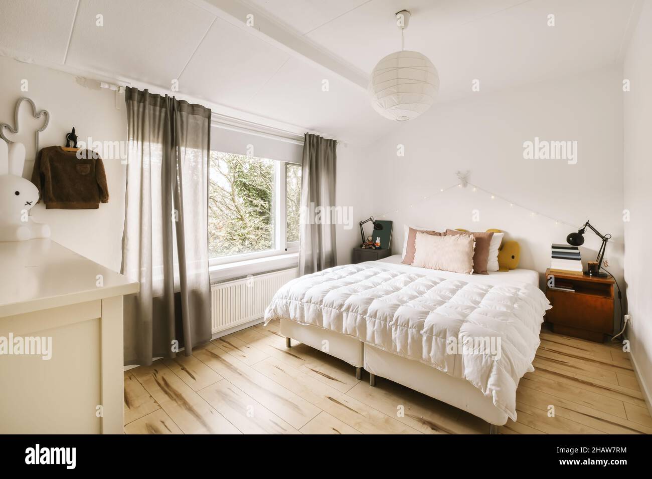Charmante petite chambre avec couvre-lit moelleux et lustre design Photo  Stock - Alamy
