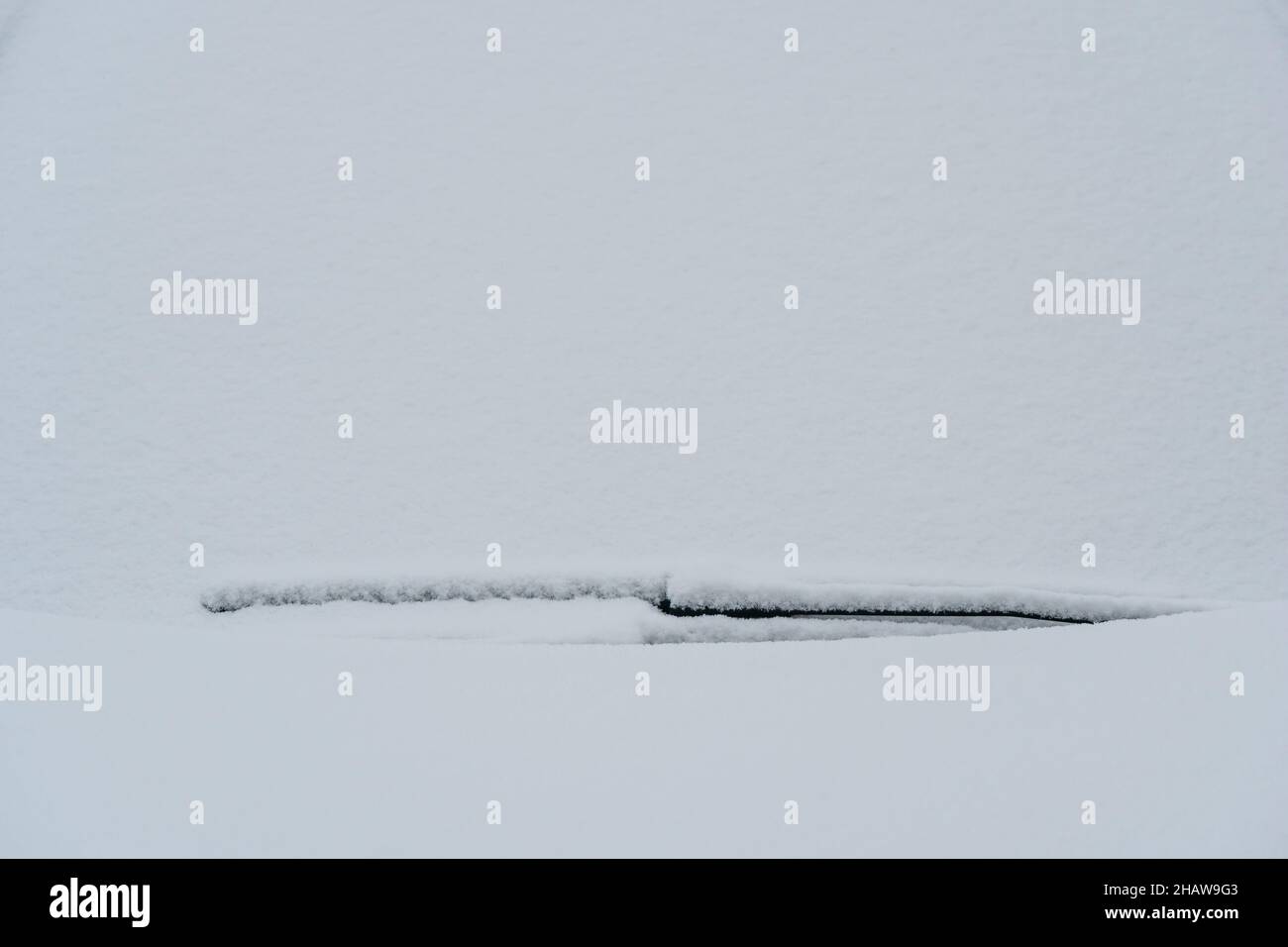 Pare-brise recouvert de neige avec balais d'essuie-glace. Neige gelée sur la voiture en hiver froid matin. Concept de conduite en hiver avec de la neige sur route. Hiver Banque D'Images