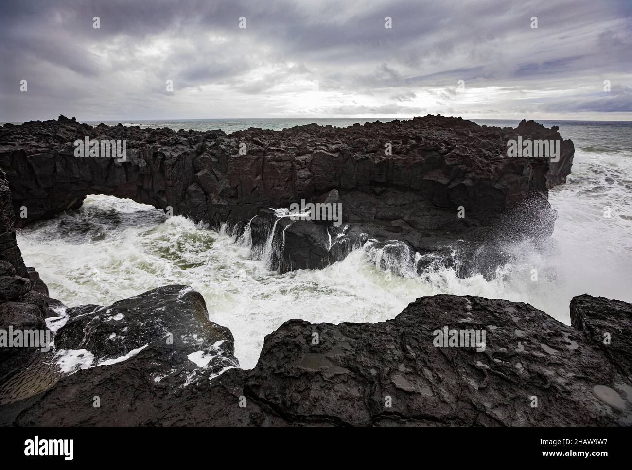 Arche de lave sur la côte volcanique à marée haute avec de hautes vagues, Ponta da Ferraria, île de Sao Miguel, Açores, Portugal Banque D'Images