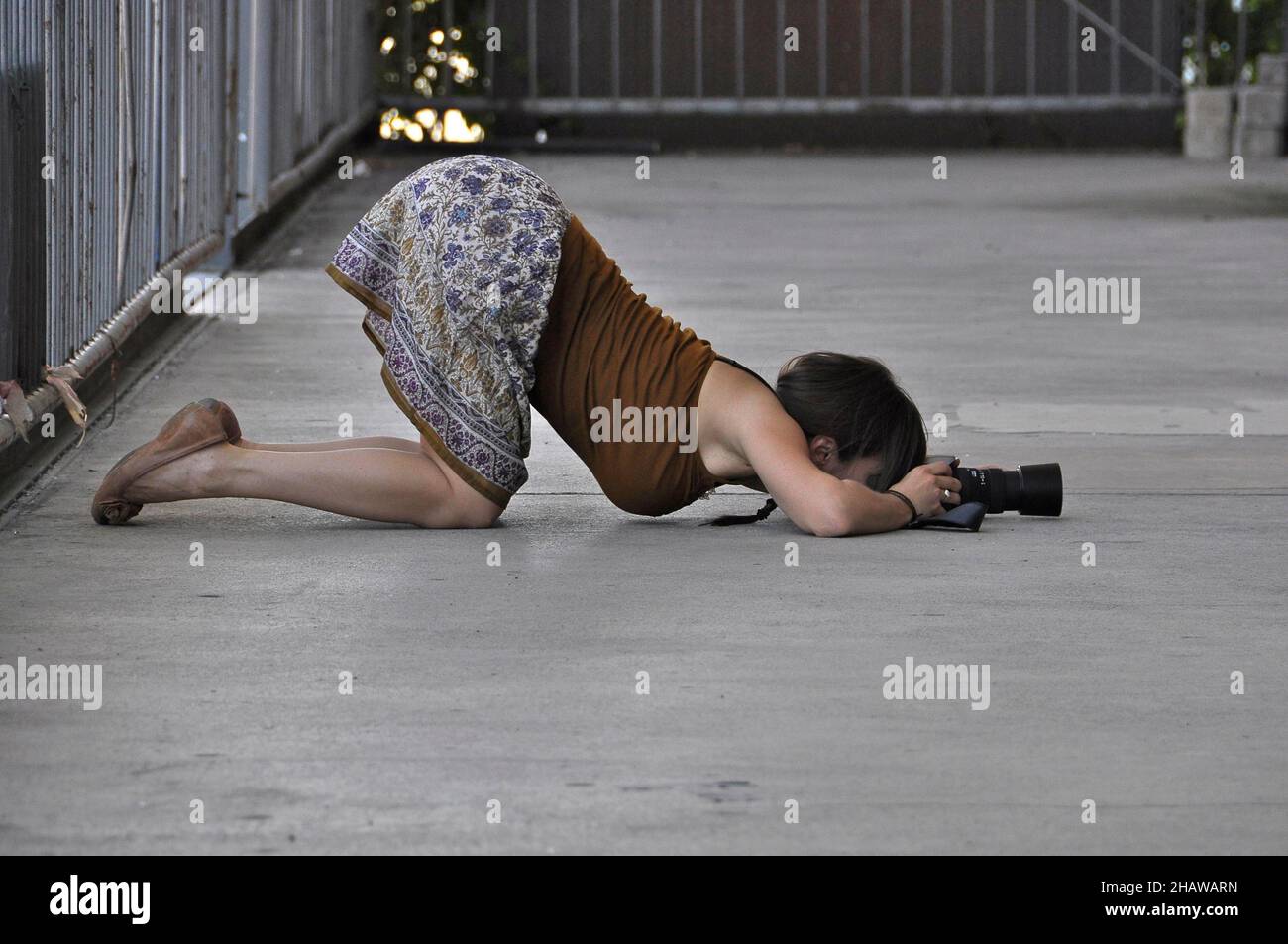 Agenouiller le photographe en position drôle, femme prend des photos agenouillée étirée, position drôle de l'appareil photo, agenouiller prend des photos sur le sol Banque D'Images